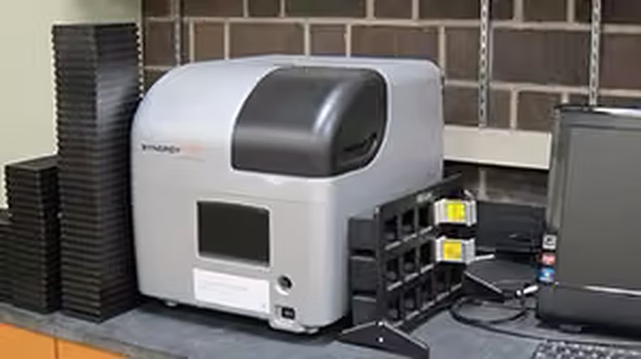 Multi-mode micro plate reader beside stacked assay plates